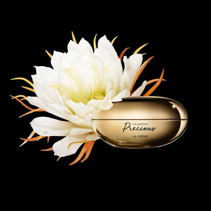 Packshot av Clarins Precious Soft Cream nära en blomma av nattens drottning mot en mörk bakgrund.